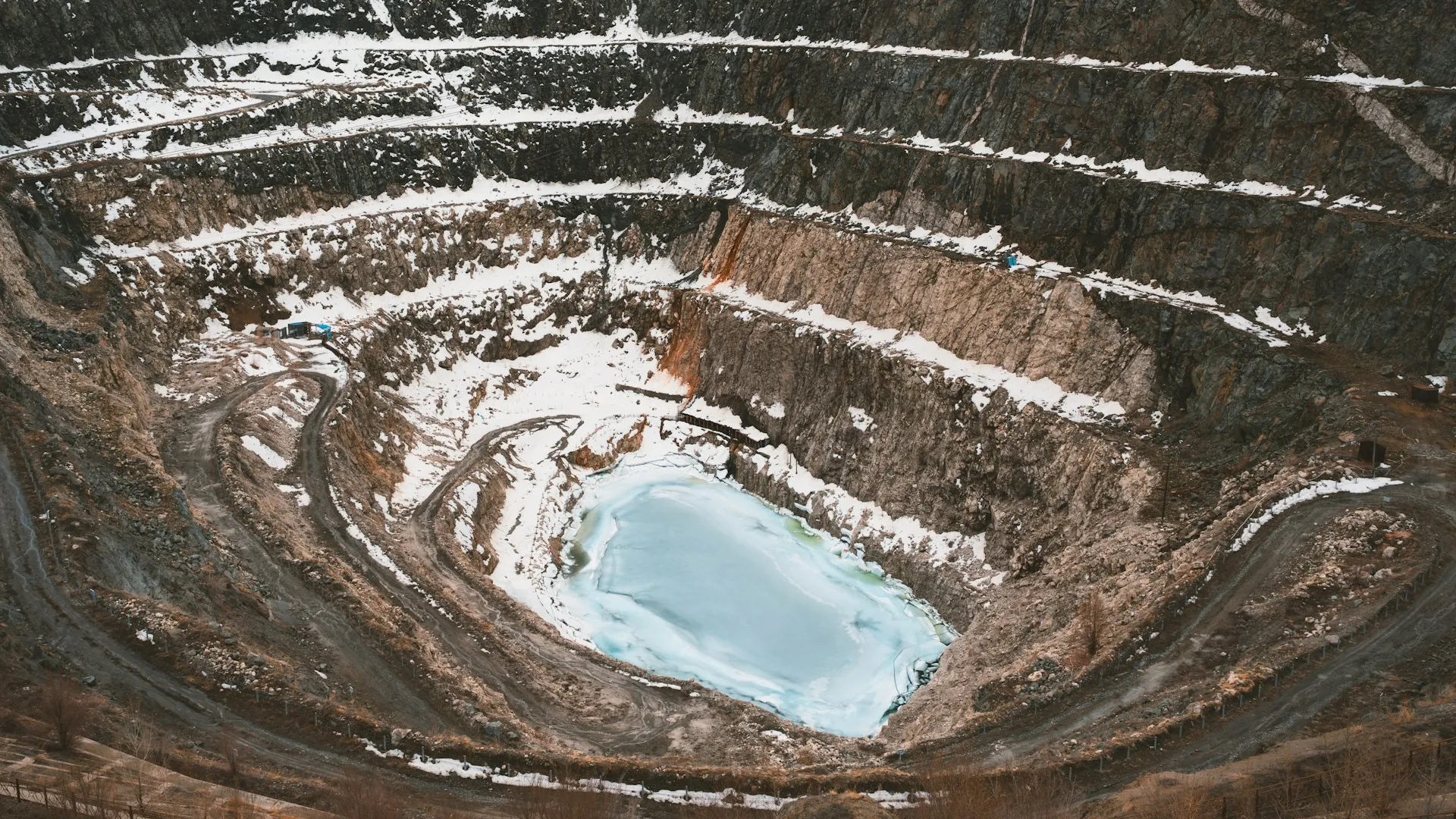 Aerial view of a large open-pit mine with water