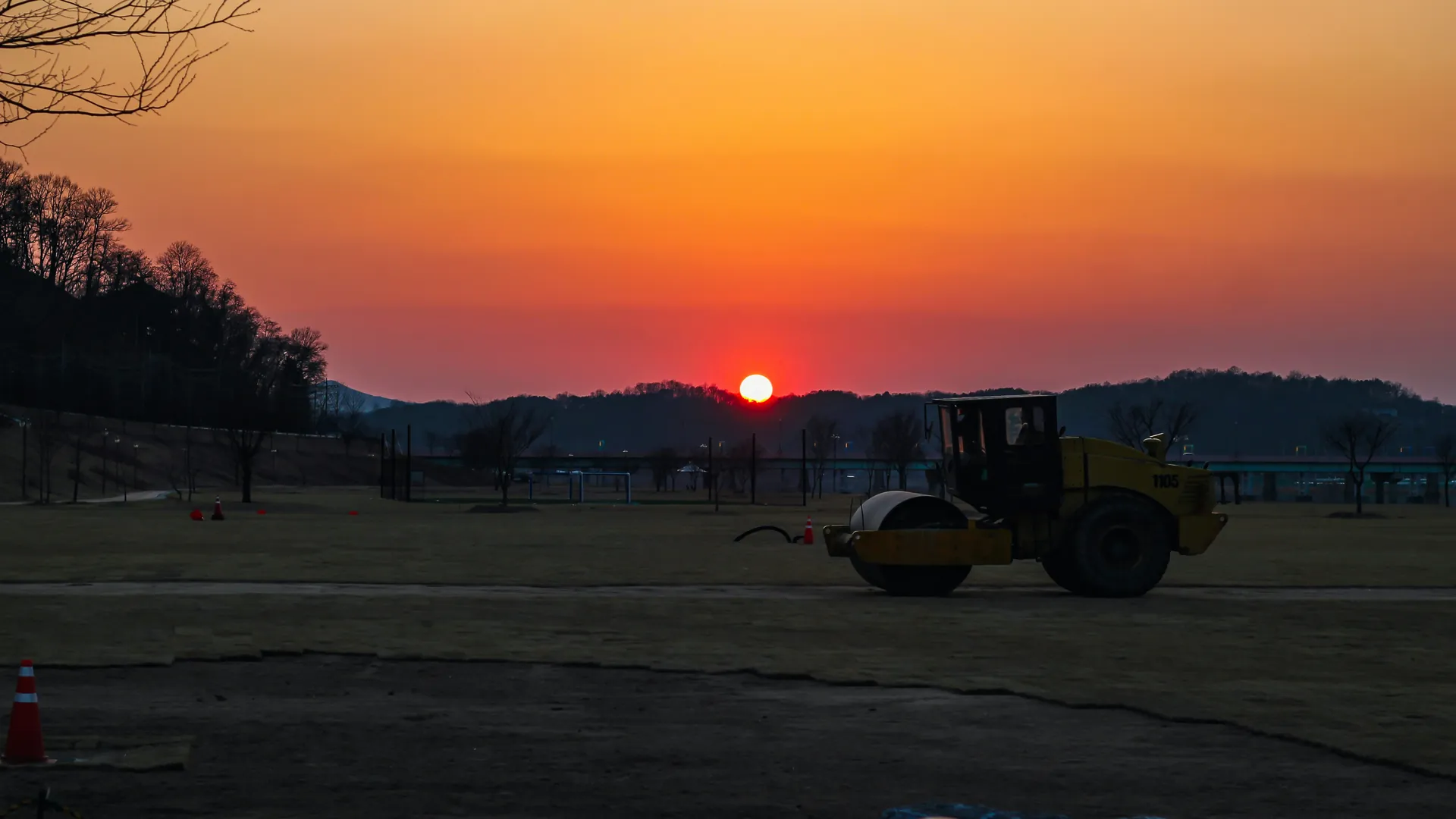 Steamroller silhouette on a field during a vibrant sunset